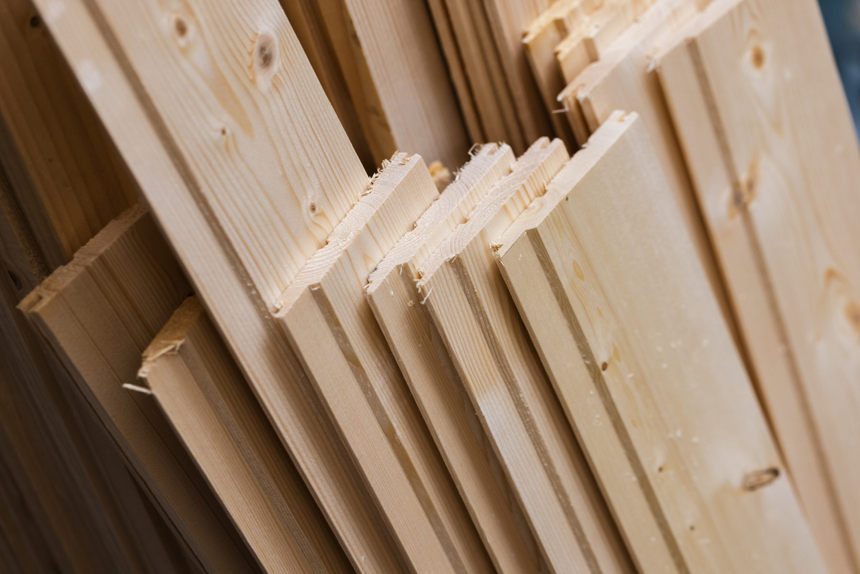 Stacked tongue-and-groove pine planks neatly arranged in a workshop, highlighting wood grain, knots and milled profiles for flooring, wall paneling, mill work and carpentry projects